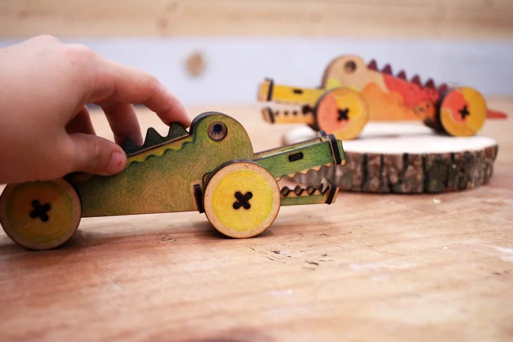 A hand holding a colorful jointed wooden crocodile toy