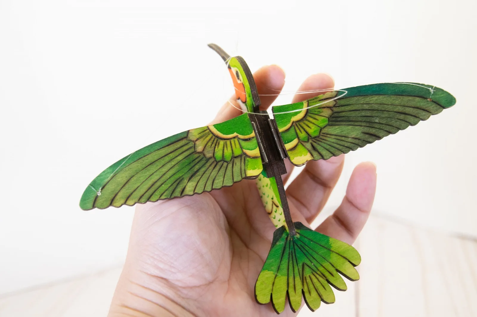 A hand-painted layered wooden bird sculpture held in one hand