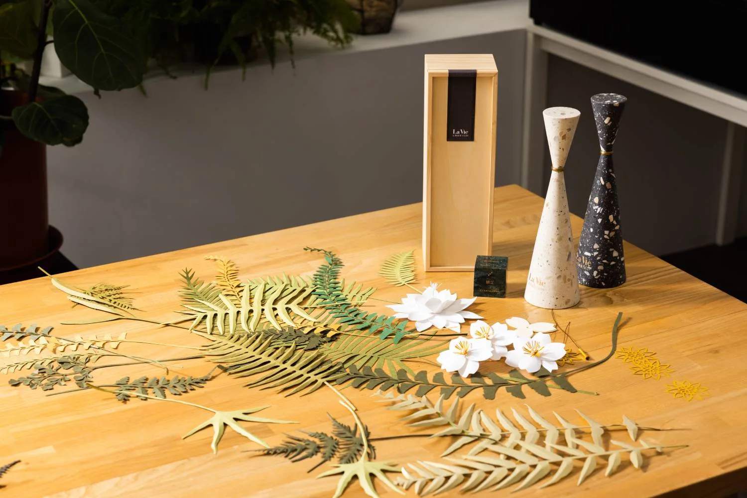 Laser-cut paper flowers and botanical forms arranged on a Studio Shikai worktable