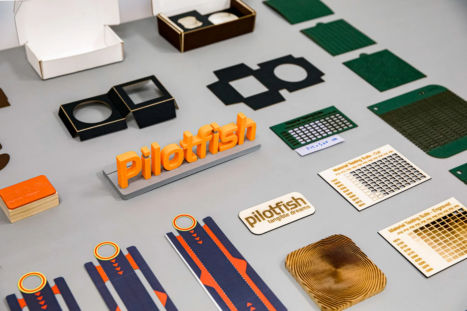 Pilotfish prototypes and laser-cut material tests arranged on a worktable
