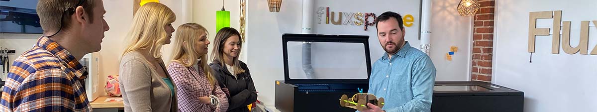 A FLUX partner demonstrating a laser cutter to a group